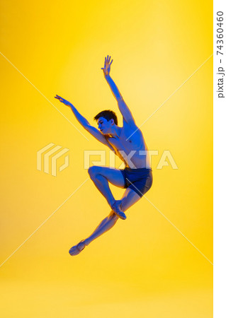 Young and graceful ballet dancer isolated on yellow studio background in neon light. Art, motion, action, flexibility, inspiration concept. Young and graceful ballet dancer isolated on yellow studio background in neon light. Art, motion, action, flexibility, inspiration concept. 74360460