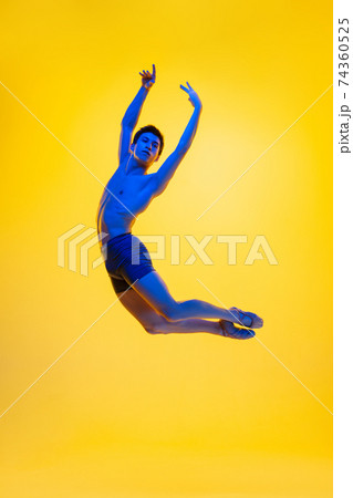 Young and graceful ballet dancer isolated on yellow studio background in neon light. Art, motion, action, flexibility, inspiration concept. Young and graceful ballet dancer isolated on yellow studio background in neon light. Art, motion, action, flexibility, inspiration concept. 74360525