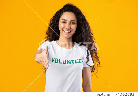 Cheerful Volunteer Woman Offering Hand For Handshake Over Yellow Background 74362093