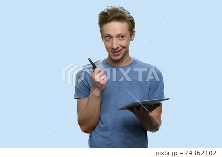 Cheerful teenager is holding a pen and a tablet. Cheerful teenager is holding a pen and a tablet. 74362102