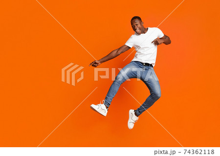 Positive black guy jumping up and showing copy space Positive black guy jumping up and showing copy space 74362118
