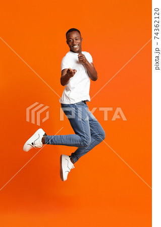 Charismatic black guy pointing at camera on orange Charismatic black guy pointing at camera on orange 74362120