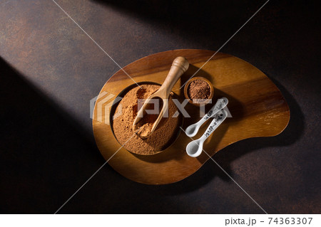 Bowl with organic carob powder on dark rustic wooden background. 74363307