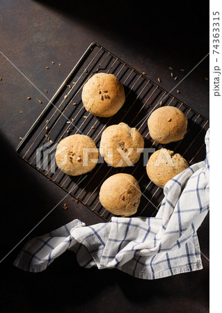 Homemade wholemeal rye wheat buns with seeds on wooden table, dark rustic background. 74363315