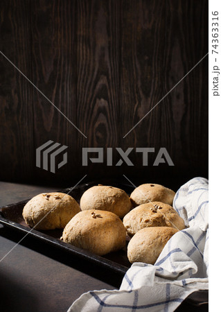 Homemade wholemeal rye wheat buns with seeds on wooden table, dark rustic background. 74363316
