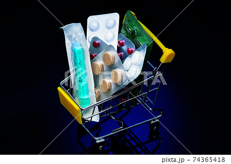 A small shopping cart is filled with pills and a syringe. Purchase of medicines and medical products A small shopping cart is filled with pills and a syringe. Purchase of medicines and medical products 74365418