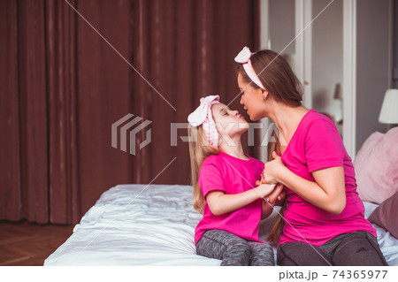 Girl and her mom sitting on the bed and make face care 74365977