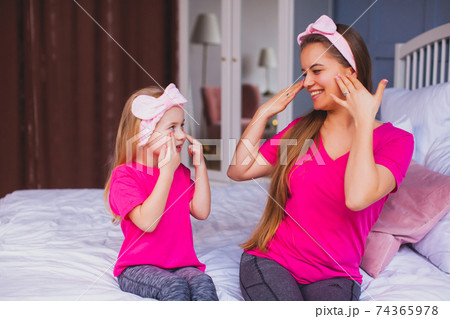 Girl and her mom sitting on the bed and make face care 74365978
