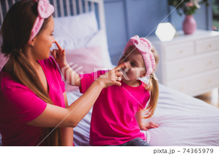 Girl and her mom sitting on the bed and make face care 74365979