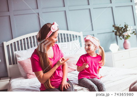 Girl and her mom sitting on the bed and make face care 74365980