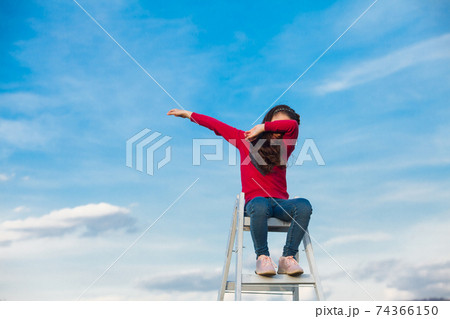 The girl is sitting on top of a ladder on the sky 74366150