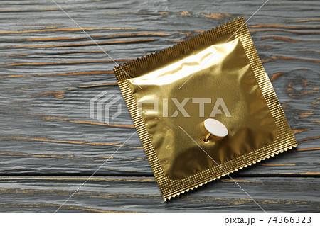 Condom with pin on wooden background, space for text 74366323
