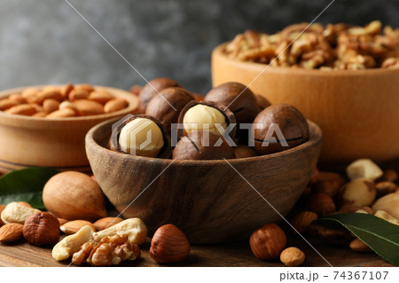 Wooden bowls with different nuts on wood background, close up 74367107