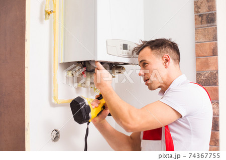 The plumber repairs a boiler at the kitchen 74367755