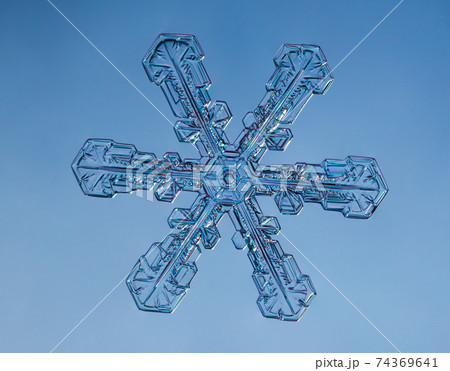 Snowflake on smooth gradient background. Macro photo of real snow crystal on glass surface. This is small snowflake with unusual pattern. 74369641