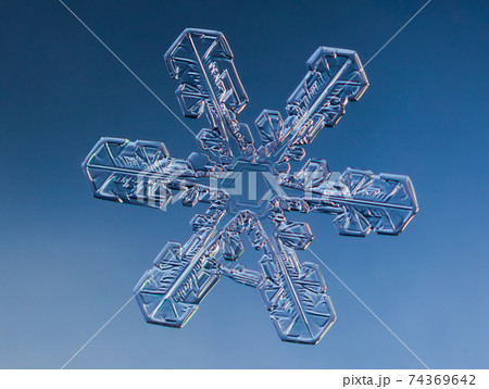 Snowflake on smooth gradient background. Macro photo of real snow crystal on glass surface. This is small snowflake with unusual pattern. Snowflake on smooth gradient background. Macro photo of real snow crystal on glass surface. This is small snowflake with unusual pattern. 74369642