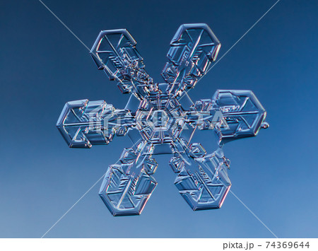 Snowflake on smooth gradient background. Macro photo of real snow crystal on glass surface. This is small snowflake with unusual pattern. Snowflake on smooth gradient background. Macro photo of real snow crystal on glass surface. This is small snowflake with unusual pattern. 74369644