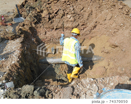 SEREMBAN, MALAYSIA -SEPTEMBER 28, 2016: Construction workers install and fixing underground utility and services pipe. Trenches were dug to the required level for them to do their works.   74370050
