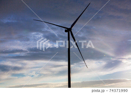 silhouette wind turbine offshore windmill made of iron with blades side view against a blue sky with clouds on sunset, alternative electricity preserving nature. 74371990