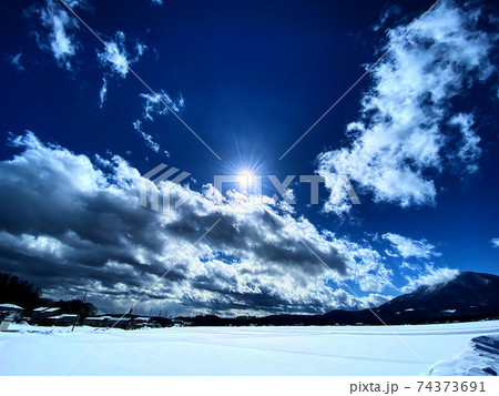 太陽の気持ちの良い光が雲や雪に反射し空の青が際立っている風景写真の写真素材 [74373691] - PIXTA