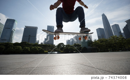 Asian woman skateboarder skateboarding in modern city 74374008