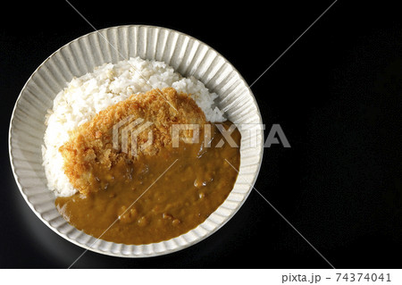 大きい豚カツが真ん中に一枚乗っているカツカレーを黒背景で撮影(俯瞰) 大きい豚カツが真ん中に一枚乗っているカツカレーを黒背景で撮影(俯瞰) 74374041