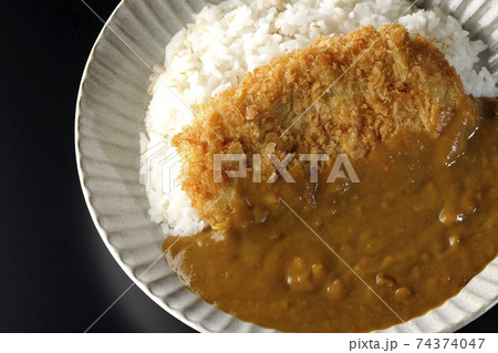 大きい豚カツが真ん中に一枚乗っているカツカレーを黒背景で撮影(俯瞰) 大きい豚カツが真ん中に一枚乗っているカツカレーを黒背景で撮影(俯瞰) 74374047