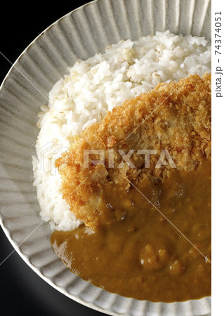 大きい豚カツが真ん中に一枚乗っているカツカレーを黒背景で撮影(俯瞰) 大きい豚カツが真ん中に一枚乗っているカツカレーを黒背景で撮影(俯瞰) 74374051