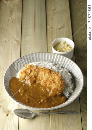 大きい豚カツが真ん中に一枚乗っているカツカレーとトッピングのチーズとスプーン 74374363