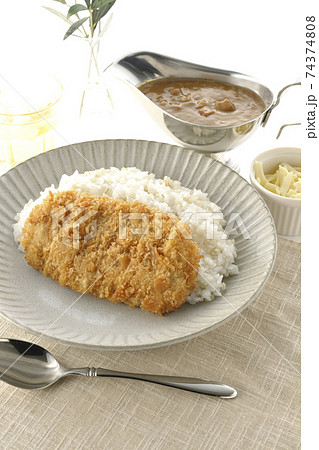 豚カツが乗ったご飯とルーが入ったカレーポットとトッピングのナチュラルチーズとお茶とオリーブの葉 豚カツが乗ったご飯とルーが入ったカレーポットとトッピングのナチュラルチーズとお茶とオリーブの葉 74374808