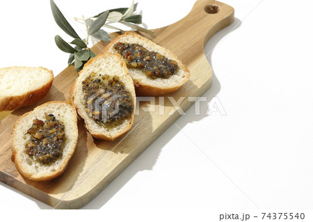 切り分けられたフランスパンの上にナッツ入りのオリーブオイルを塗って食べる（白背景） 74375540