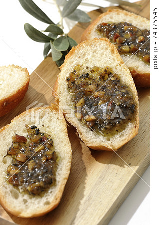切り分けられたフランスパンの上にナッツ入りのオリーブオイルを塗って食べる 白背景 の写真素材