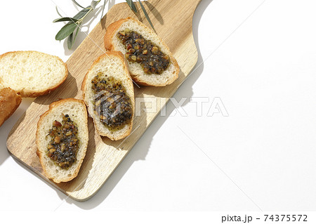 切り分けられたフランスパンの上にナッツ入りのオリーブオイルを塗って食べる 白背景 の写真素材