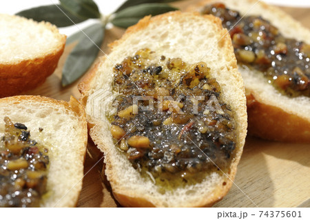 切り分けられたフランスパンの上にナッツ入りのオリーブオイルを塗って食べる（白背景） 74375601