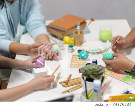 Teenagers hands painting easter eggs, preparing for easter festival with painting tools 74376234