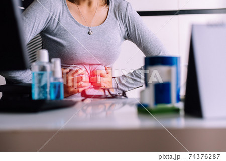 Women suffering from abdominal pain,Period cramps,Hands squeezing belly,Stomach pain ,Woman having painful stomach ache during working at home 74376287