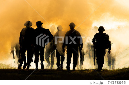 Silhouettes of army soldiers in the fog against a sunset, marines team in action, surrounded fire and smoke, shooting with assault rifle and machine gun, attacking enemy 74378046