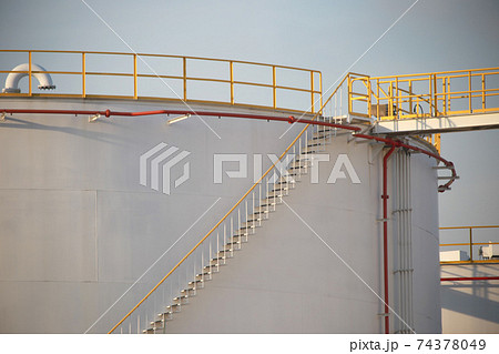 large Industrial tanks for petrol and oil with blue sky.Fuel tanks at the tank farm. metal stairs on the side of an industrial oil container.Staircase on big fuel tank large Industrial tanks for petrol and oil with blue sky.Fuel tanks at the tank farm. metal stairs on the side of an industrial oil container.Staircase on big fuel tank 74378049