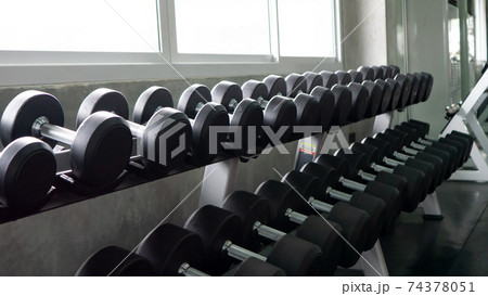 Black Drumbbells on rack in fitness gym Black Drumbbells on rack in fitness gym 74378051