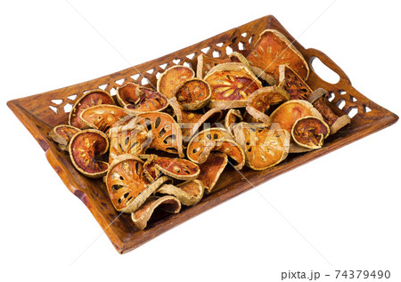 Wooden tray with dried bael fruit isolated on white background. Wooden tray with dried bael fruit isolated on white background. 74379490
