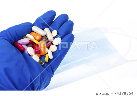 Hand in medical glove holds colored pills, pills and capsules. 74379554