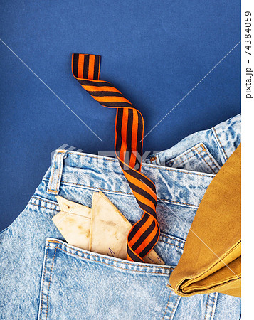 Modern jeans and symbols of victory in the Second World War. St. George's ribbon, military cap, cartridges and letters from the front. The concept of victory on May 9 for a postcard background Modern jeans and symbols of victory in the Second World War. St. George's ribbon, military cap, cartridges and letters from the front. The concept of victory on May 9 for a postcard background 74384059