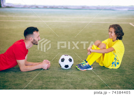 Boy in yellow uniform resting after the game and talking to his coach 74384405