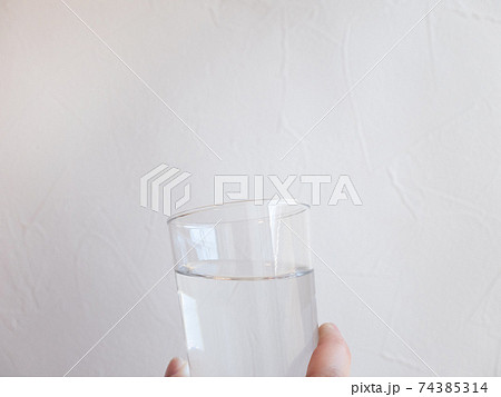 水が入った透明グラスを持つ手。水分補給、水を飲む。 水が入った透明グラスを持つ手。水分補給、水を飲む。 74385314