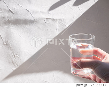 水が入った透明グラスを持つ手。水分補給、水を飲む。 74385315