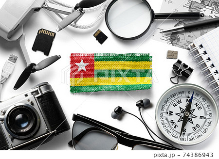 Flag of Togo and travel accessories on a white background. Flag of Togo and travel accessories on a white background. 74386943