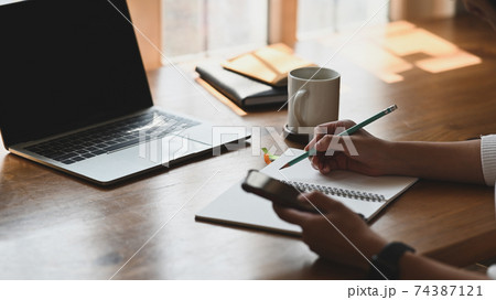 Cropped shot of young beautiful writer making up the story while sitting at the modern wooden table in front the black screen laptop in her relaxation time. Women lifestyle concept. Cropped shot of young beautiful writer making up the story while sitting at the modern wooden table in front the black screen laptop in her relaxation time. Women lifestyle concept. 74387121