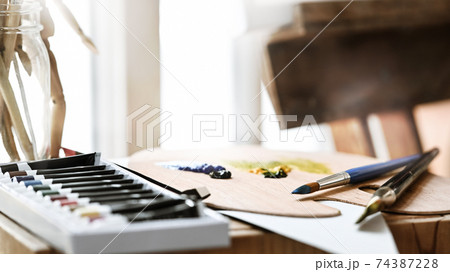 Artist equipment putting on wooden working table. Paint brush, oil color, palette putting together on working artist working desk. Cluttered workplace concept. Artist equipment putting on wooden working table. Paint brush, oil color, palette putting together on working artist working desk. Cluttered workplace concept. 74387228