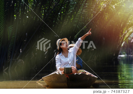Traveler young woman wearing hat and pointing finger to something Traveler young woman wearing hat and pointing finger to something 74387327