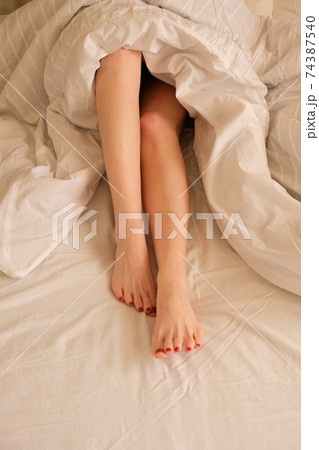 Soft photo of woman's feet under a blanket, top view point Soft photo of woman's feet under a blanket, top view point 74387540